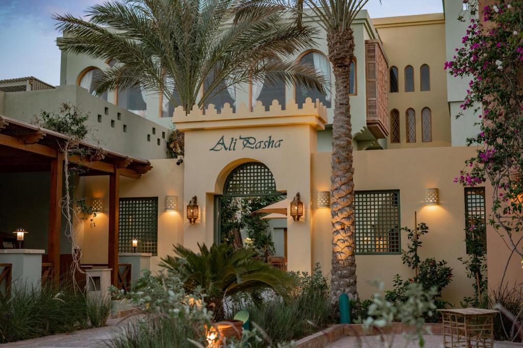 a hotel with a palm tree in front of a building at Ali Pasha Hotel in Hurghada