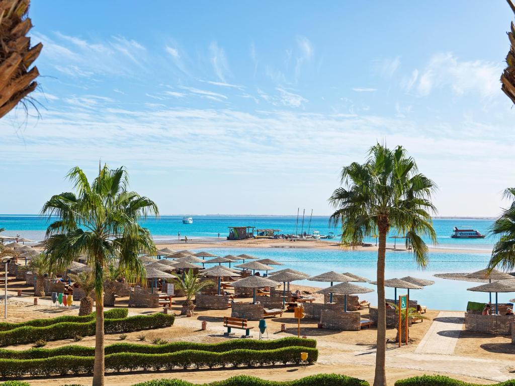 una playa con palmeras, sombrillas y el océano en Club Paradisio El Gouna Red Sea, en Hurghada