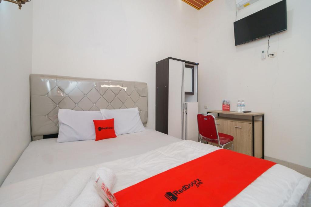 ein Schlafzimmer mit einem weißen Bett mit einer roten Decke in der Unterkunft RedDoorz @ Jalan Sultan Agung Lampung in Kedaton