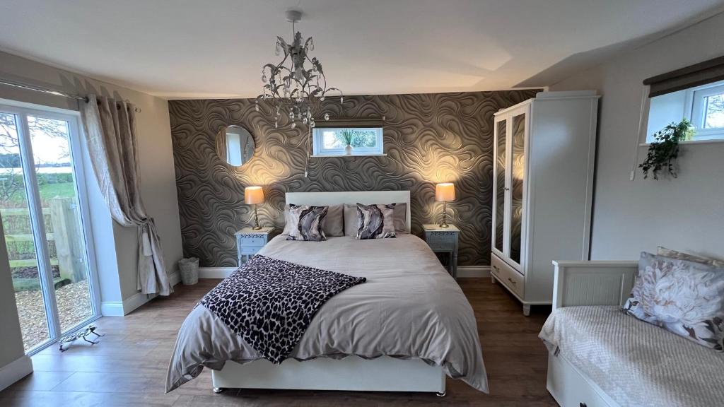 Un dormitorio con una cama grande y una lámpara de araña. en Runway Cottage, en Coningsby