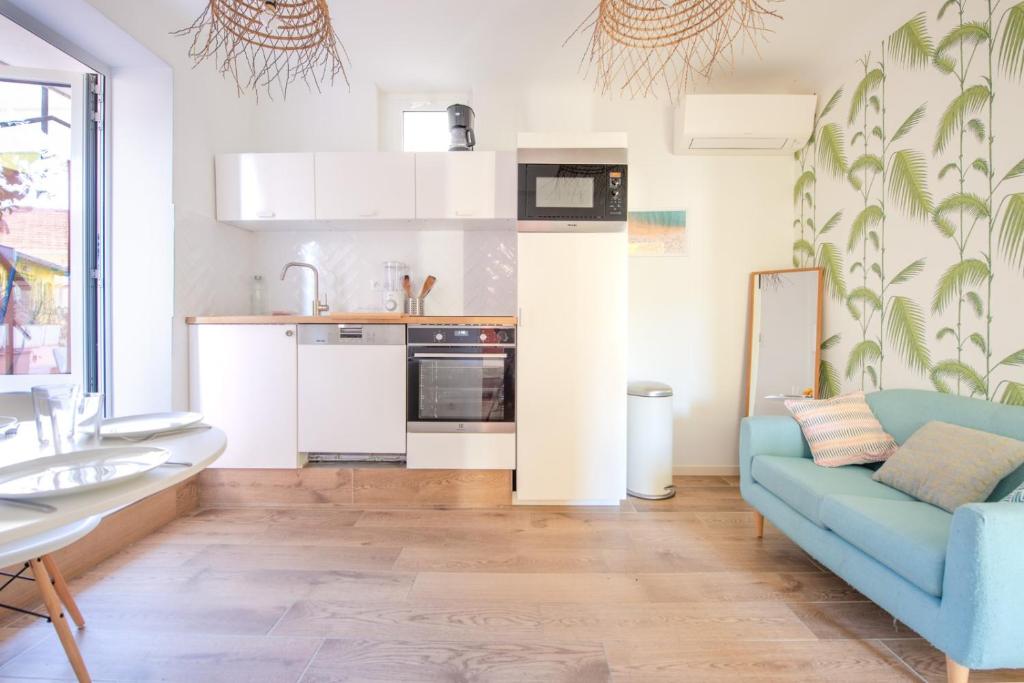 un salon avec un canapé bleu et une cuisine dans l'établissement Maison Giribaldi, à Nice