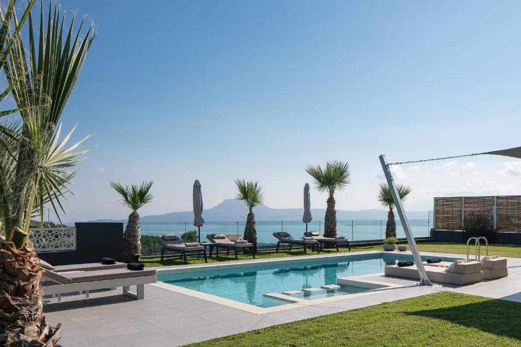 a swimming pool with chaise lounge chairs and palm trees at Villa Niolos I in Marathi