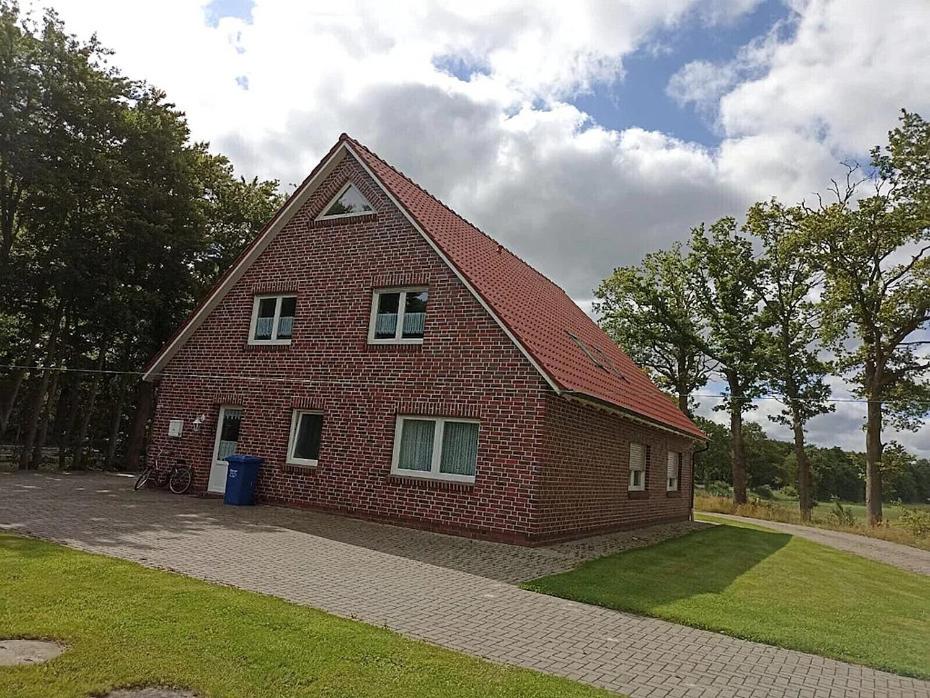 a red brick house with a gambrel roof at Ferienwohnung Zur Kuhweide in Dunum