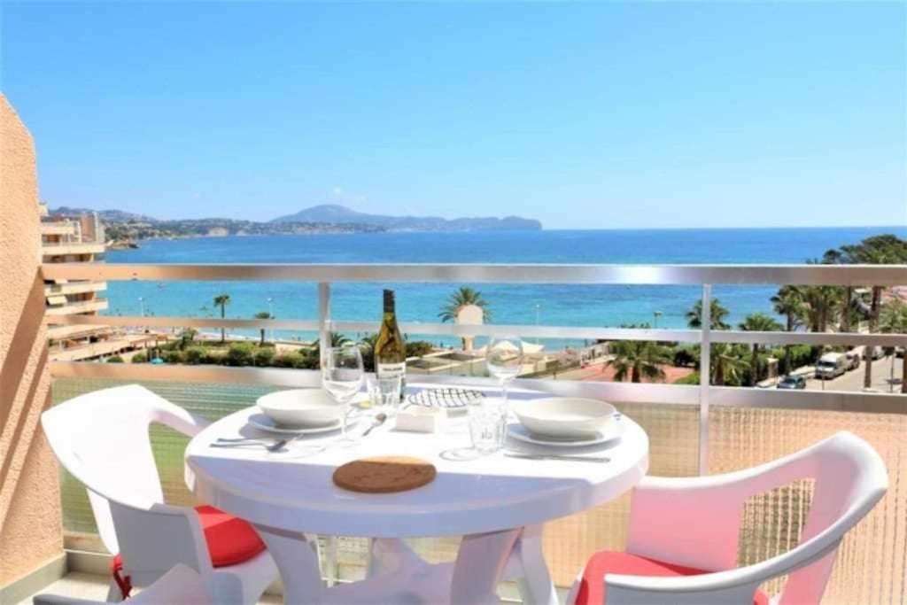 uma mesa branca e cadeiras numa varanda com o oceano em 3F 1ª línea de playa con vistas al mar em Calpe