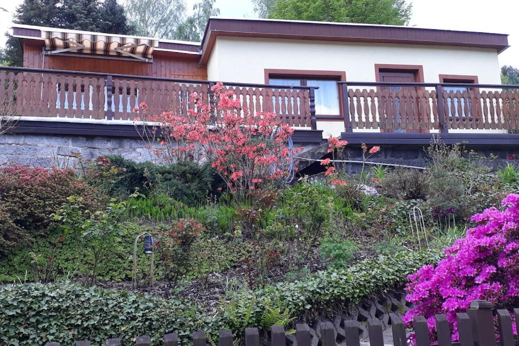a house with a balcony and flowers in front of it at Bungalow blühende Oase in Sebnitz