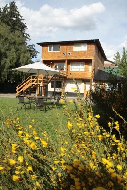 una casa con una mesa y una sombrilla en un campo en Apart Dry Fly, en Junín de los Andes