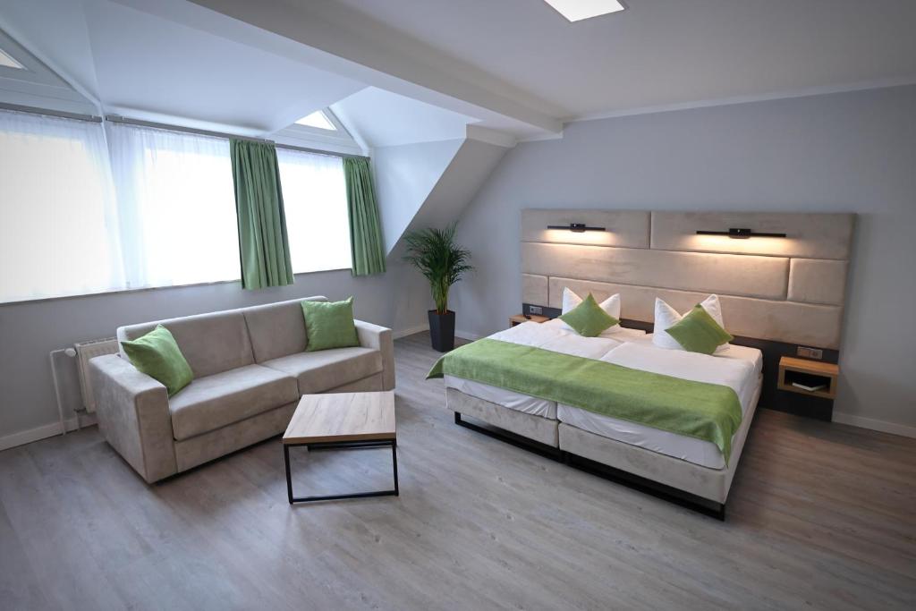 Un dormitorio grande con una cama y un sofá. en Hotel und Restaurant Kranichsberg, en Woltersdorf