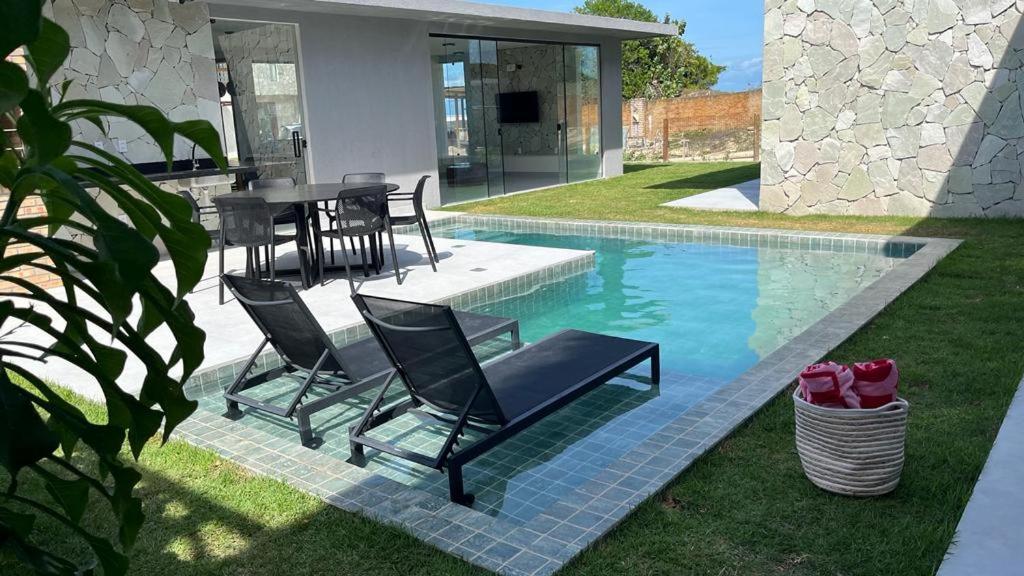 una piscina con sillas y una mesa junto a una casa en Villa 56, en São Miguel do Gostoso