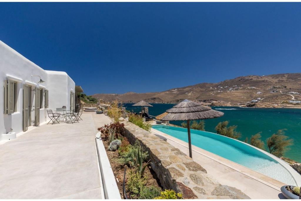 uma casa com piscina e guarda-sol em Elite Mykonos Villa - Villa Roxane - Private Pool - 6 Bedrooms - Beachfront - Ftelia em Dexamenes