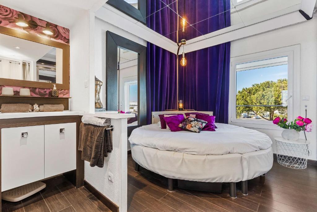 a bedroom with a bed with purple walls and a mirror at La vie en rose naturiste - Port Nature in Cap d'Agde