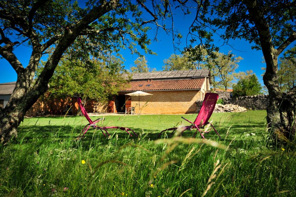 two red chairs in the grass in front of a house at Domaine Lagardelle Rocamadour in Rocamadour