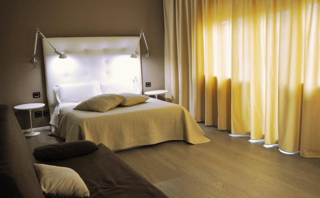 a bedroom with a white bed with a yellow blanket at Hotel Salus in Pescara