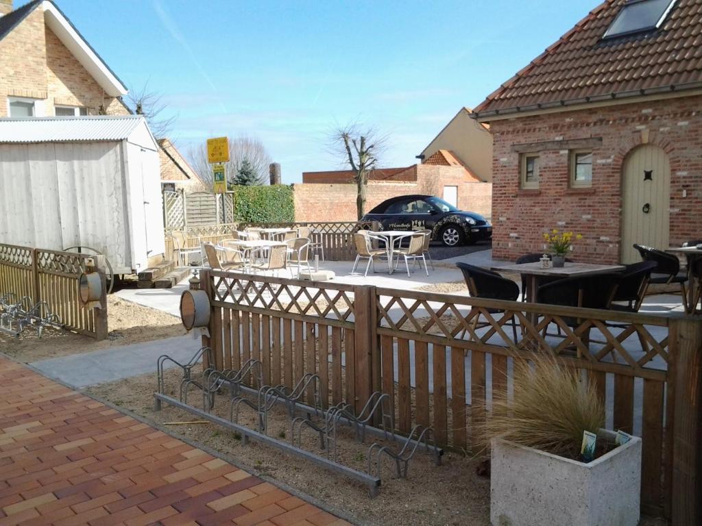 eine Terrasse mit Tischen, Stühlen und einem Zaun in der Unterkunft B&B 't Hemelbedje in Nieuwpoort