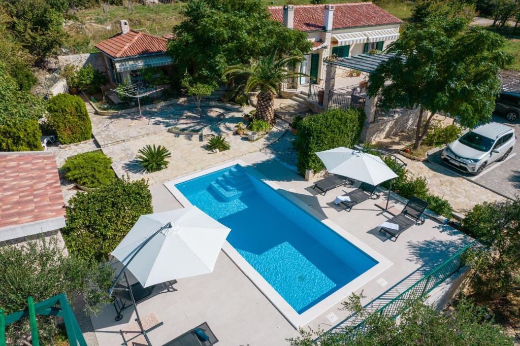 einen Blick über einen Pool mit Sonnenschirmen und ein Haus in der Unterkunft Villa Mimosa in Novalja