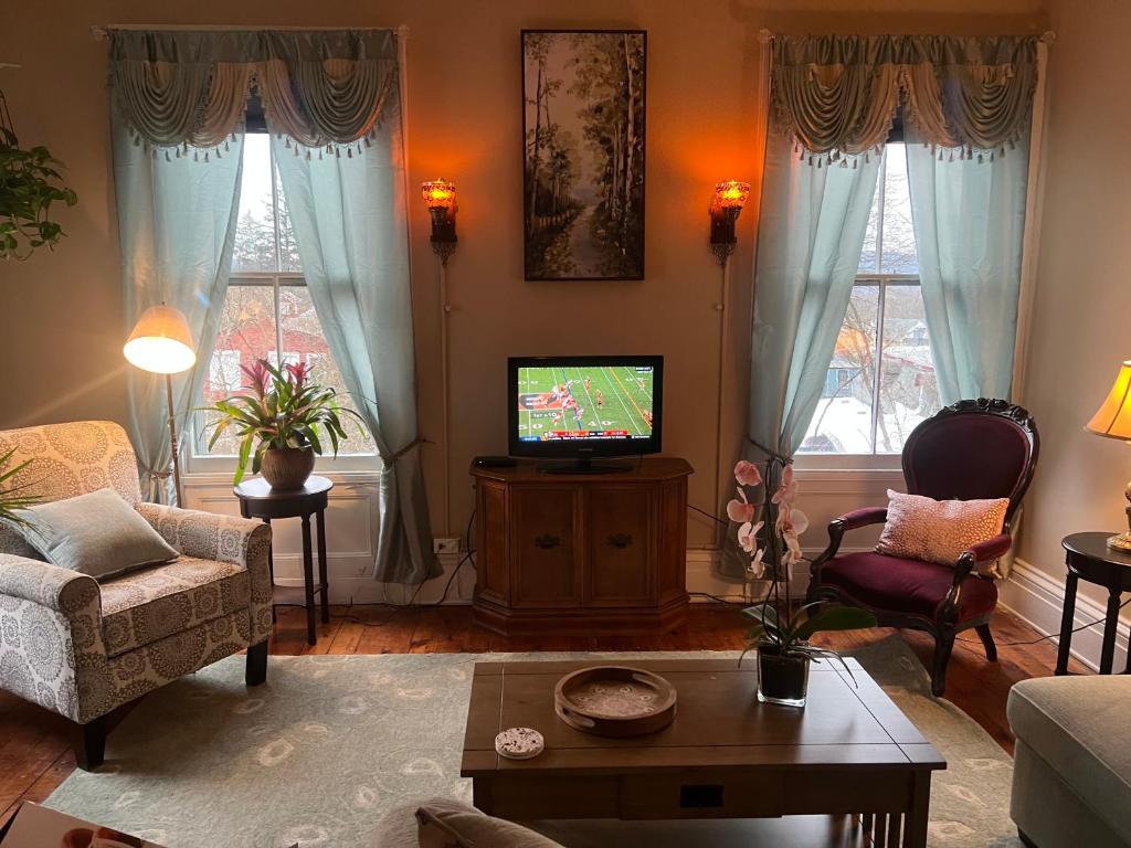 un soggiorno con TV, divano e sedie di 1 Br Private Victorian Apt in convenient City location on 5 acre, sleeps 4 a Poughkeepsie