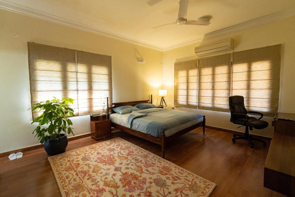 a bedroom with a bed and a chair and windows at Luho 187 in Bangalore