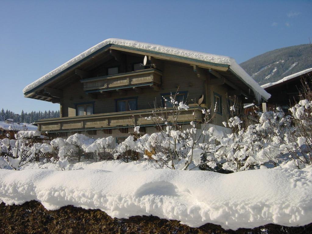 una cabaña de madera con nieve delante en Ferienwohnung Enn, en Neukirchen am Großvenediger