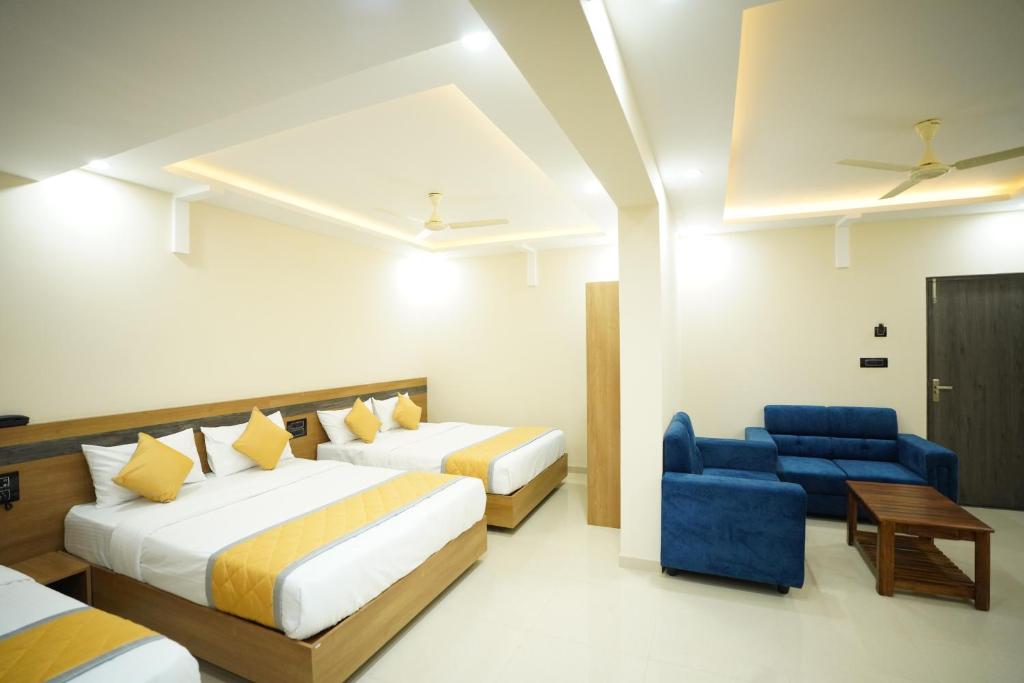 a hotel room with two beds and a blue chair at Hotel Mangalore Stay INN in Mangalore