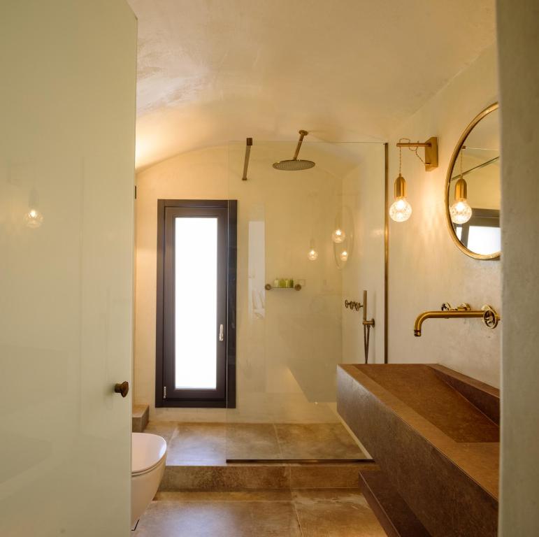 a bathroom with a sink and a toilet and a mirror at LF Suites & Villas in Imerovigli