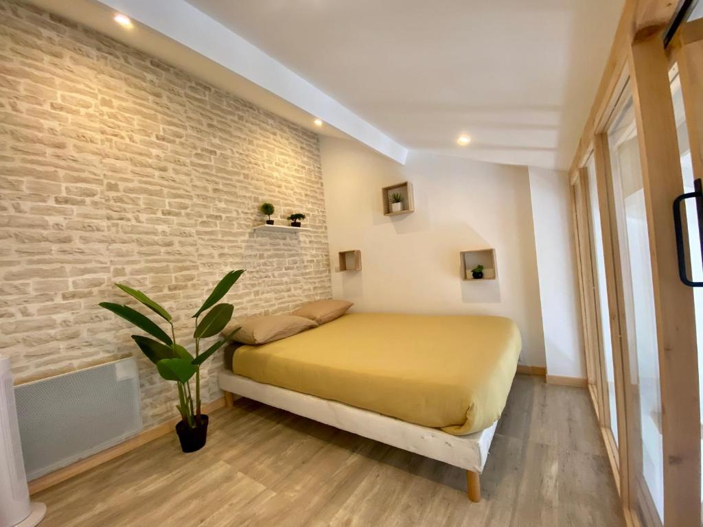 Un dormitorio con una cama amarilla y una pared de ladrillo en Bel appartement à deux minutes de la plage, en Courseulles-sur-Mer