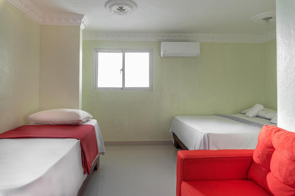 a room with two beds and a red couch at Spacious Quiet Double Room Near Megacentro - 10 min drive in La Viva