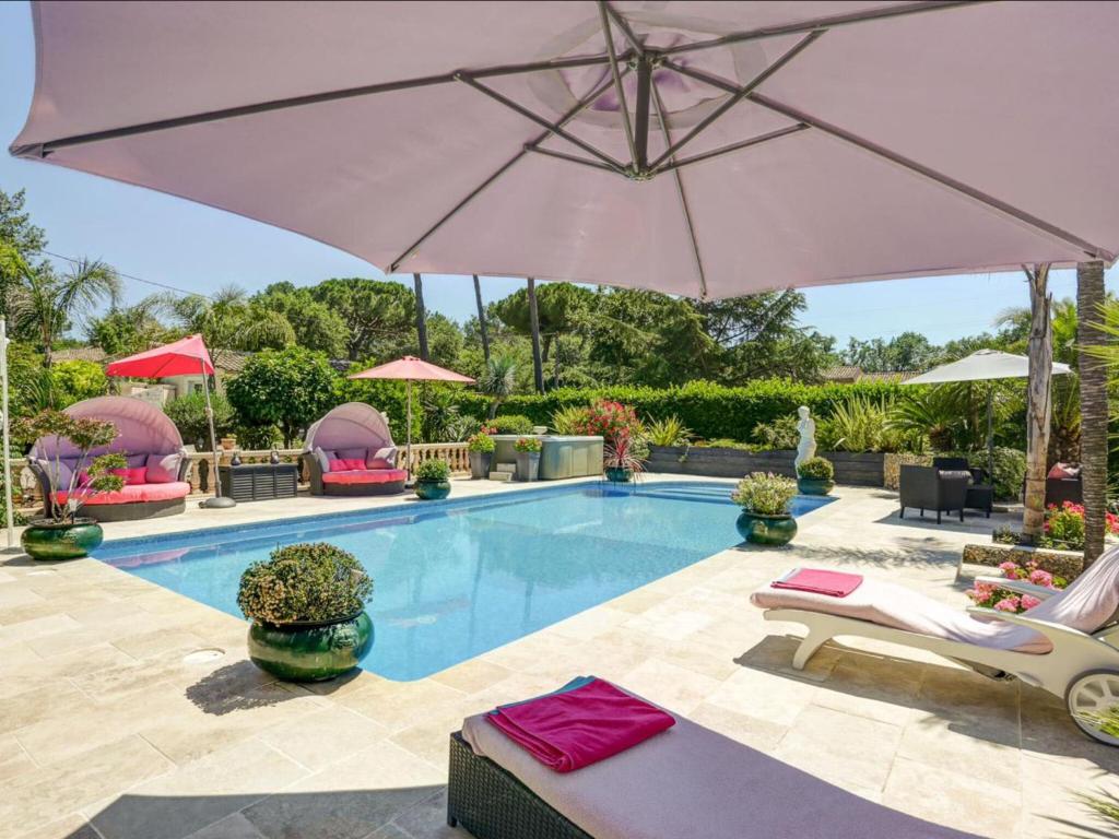 ムアン・サルトゥーにあるLavish Villa in Mouans Sartoux with Saunaのパラソル、椅子、プール付きのスイミングプールを提供しています。