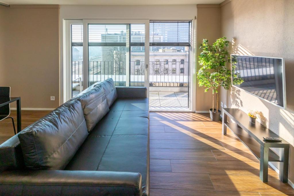 Cette chambre dispose d'un balcon et d'un canapé en cuir. dans l'établissement SKYLINE Exclusive Penthouse Apartments, à Bâle