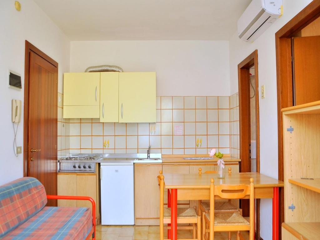 a kitchen with a wooden table and a table and a couch at Luminous flat 400 m from the beach for 4 guests in Bibione