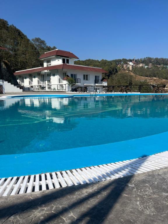 a large swimming pool with a house in the background at Nagarkot Resort PVt. Ltd in Nagarkot