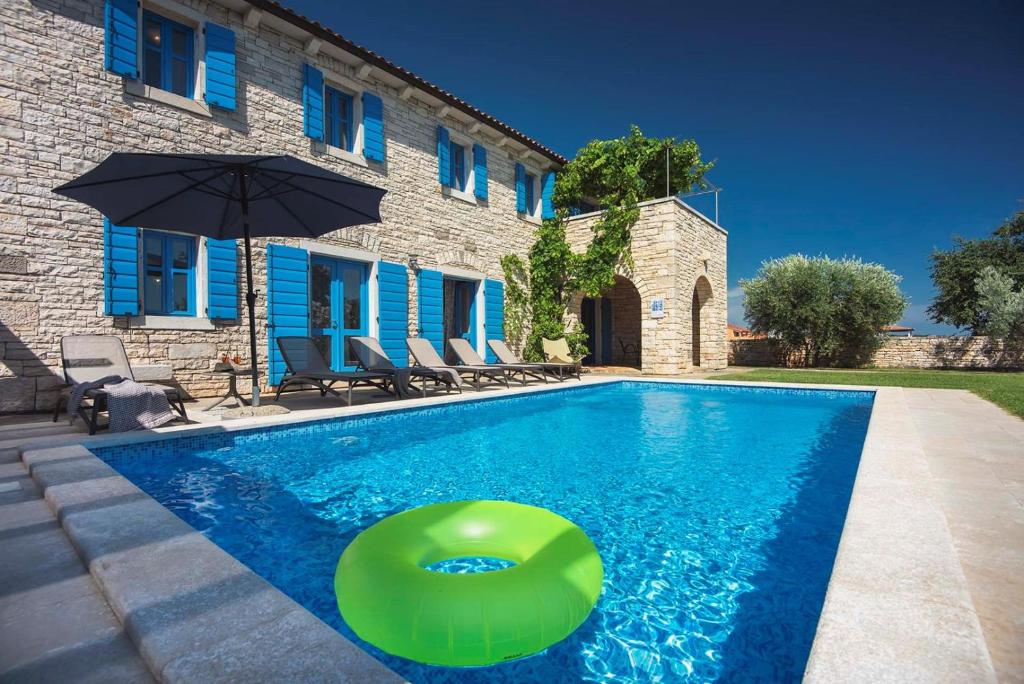 ein Schwimmbad mit einem grünen Objekt vor einem Haus in der Unterkunft Villa Nina in Vodnjan