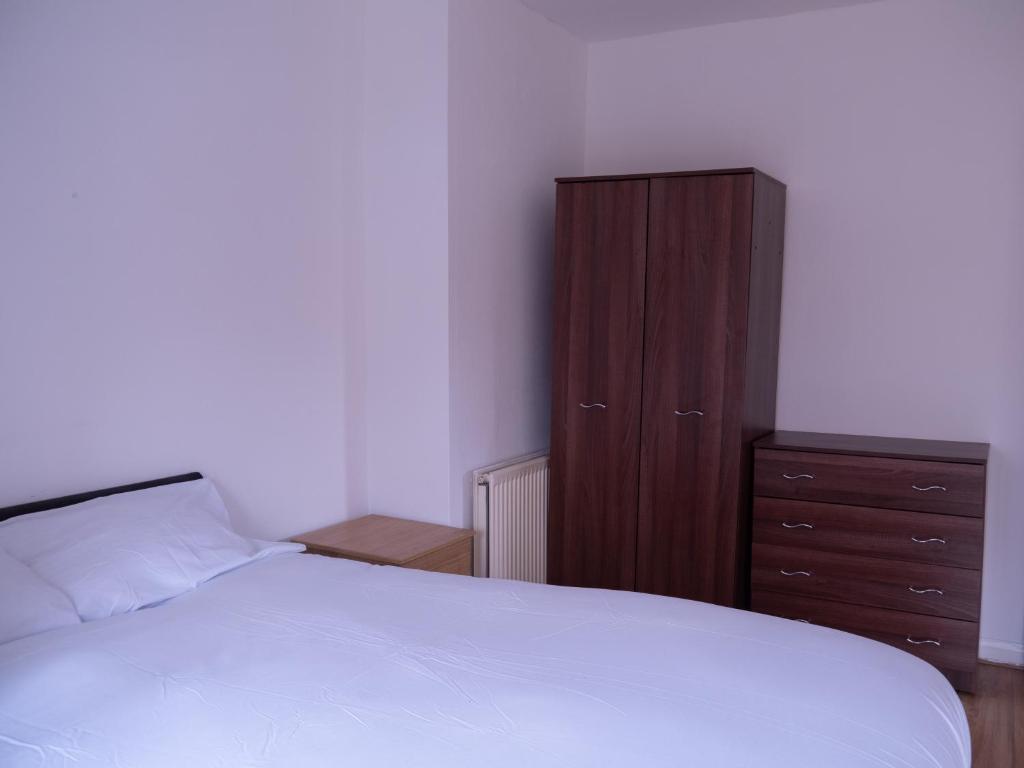 a bedroom with a bed and a wooden cabinet at Convenient 3BR close to QE Hospital & University of Birmingham in Birmingham