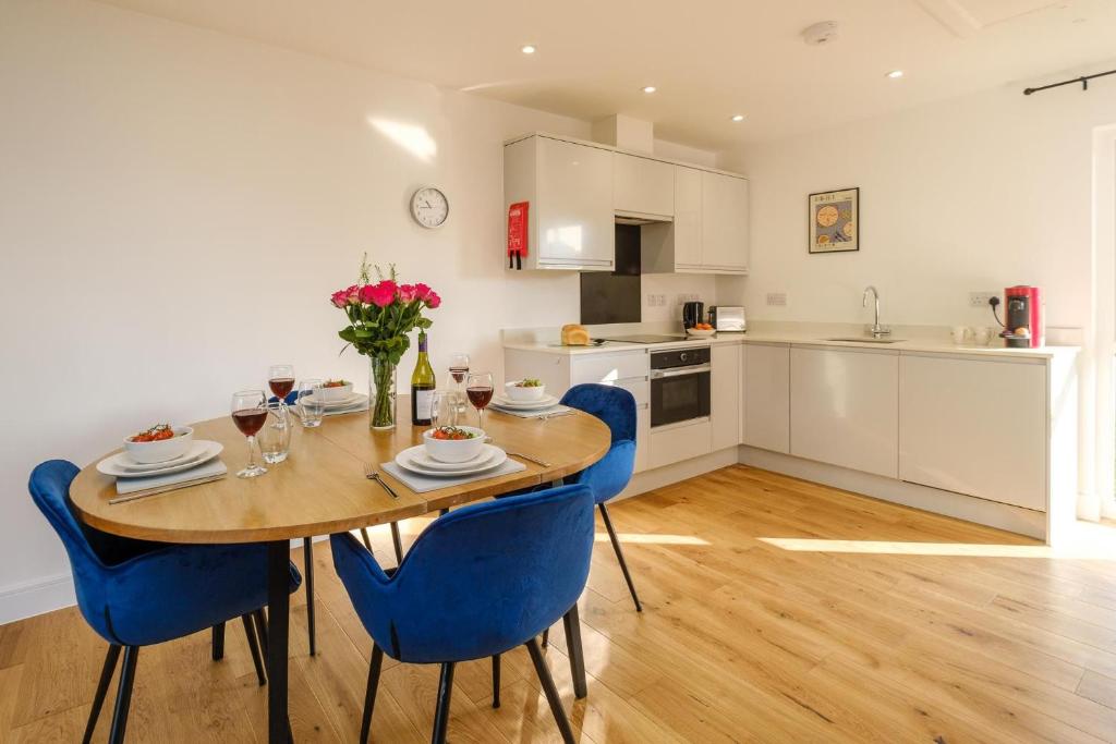 a kitchen and dining room with a wooden table and blue chairs at Three Tuns - Garden Suite 2 in Wickham Market