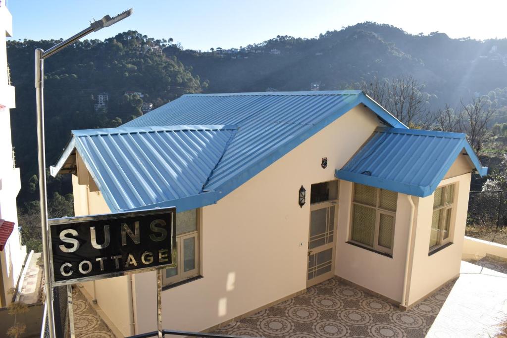 un pequeño edificio con techo azul y una cabaña soleada en Idyllic Private Cottage w/King Bed + Mountain view en Kasauli