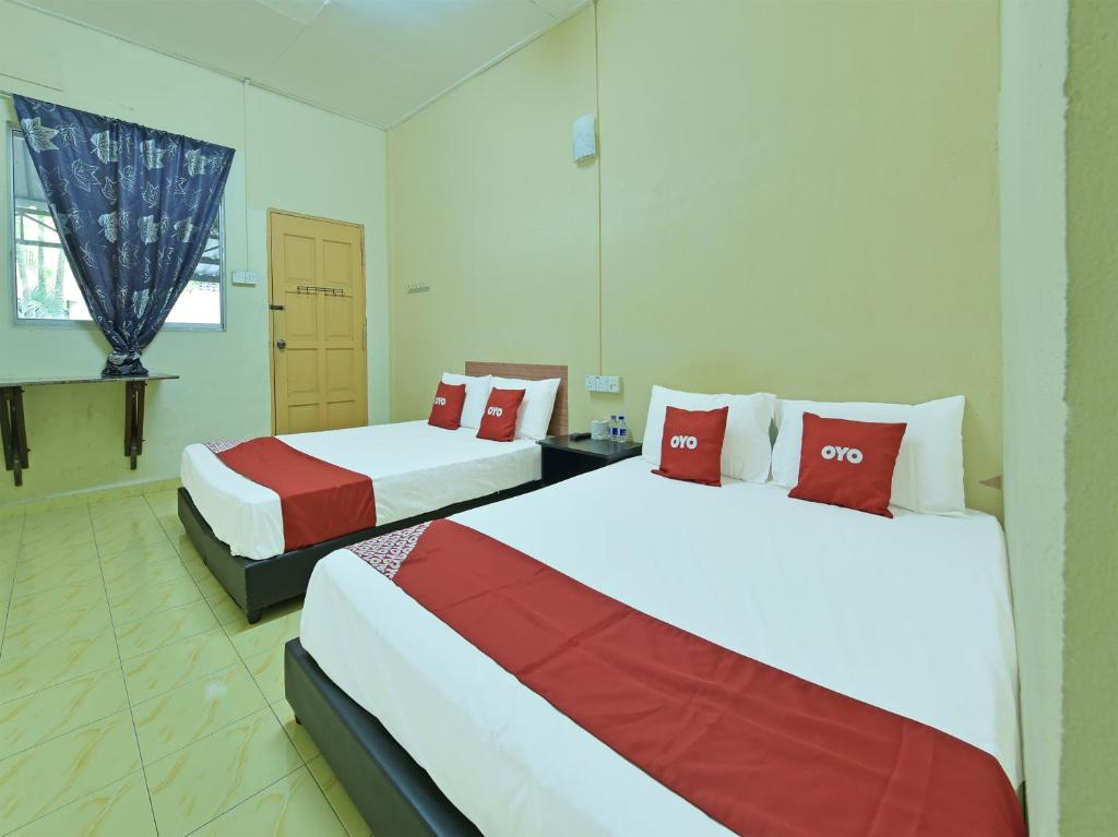 Habitación con 2 camas en rojo y blanco en OYO 90706 Empire Inn 2 en Kota Bharu