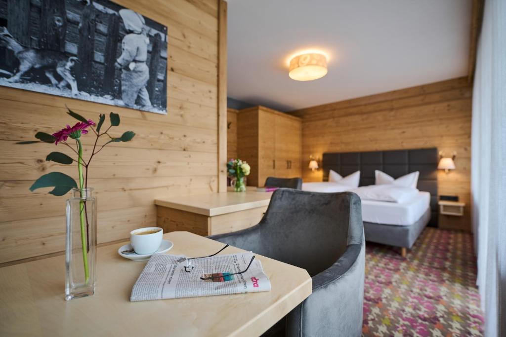 una habitación de hotel con una cama y una mesa con un jarrón de flores en Hotel Bannwaldsee, en Halblech