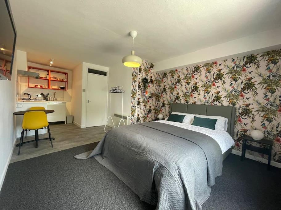 a bedroom with a large bed and floral wallpaper at Modern studio apartment; 10min walk to town & quay in Exeter