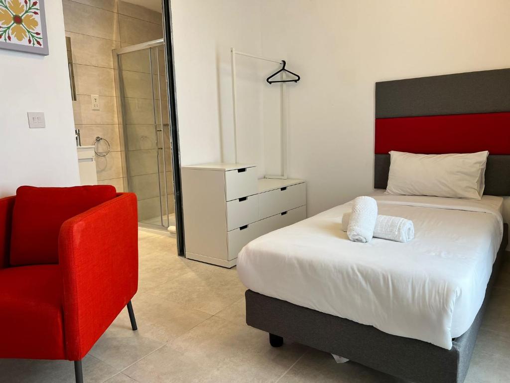 a bedroom with a bed and a red chair at Casa Domenico 8 in Valletta