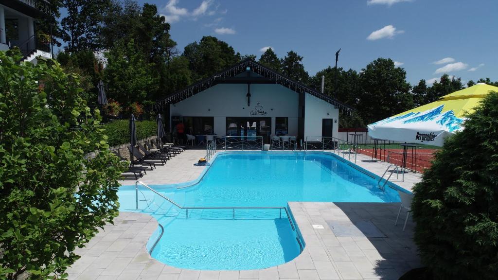 a large swimming pool with a building in the background at Casa YDA in Horezu