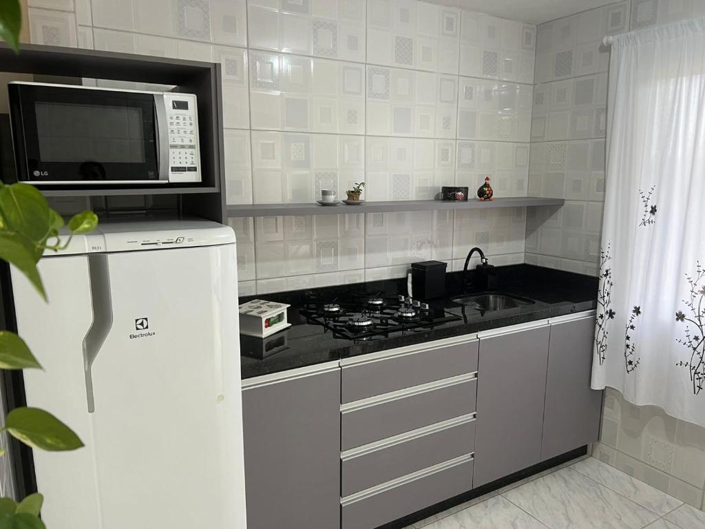 a kitchen with a stove and a microwave at Apartamento Studio com banheiro privativo in São José