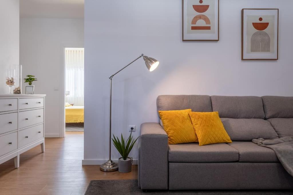 sala de estar con sofá gris y almohadas amarillas en Apartamento novo e acolhedor na Praia da Barra, en Gafanha da Nazaré