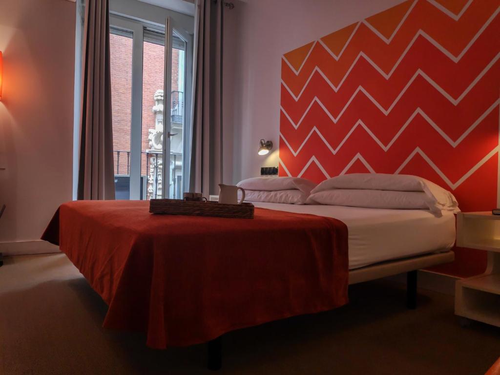 a bedroom with a bed with a red head board at Hostal Santa Ana Colors in Madrid