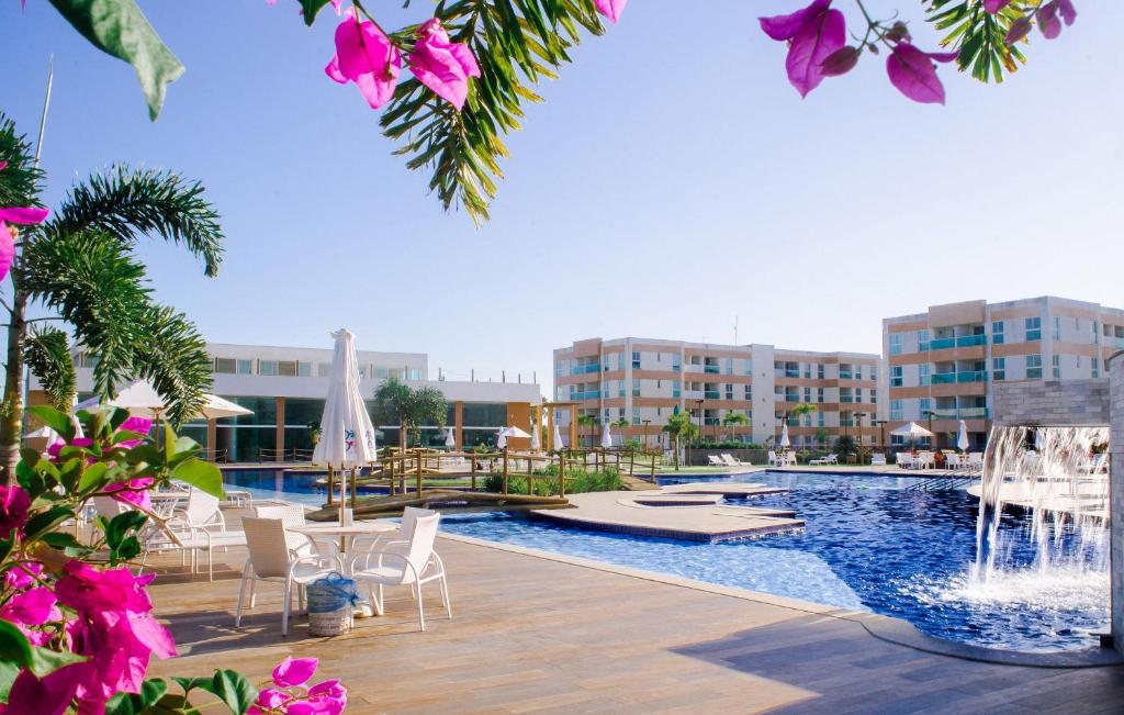 a swimming pool with chairs and a resort at Flat em Porto de Galinhas - Muro Alto Clube in Porto De Galinhas