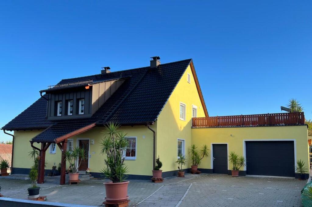 a yellow house with a black roof at Ferienwohnung Erika in Waischenfeld