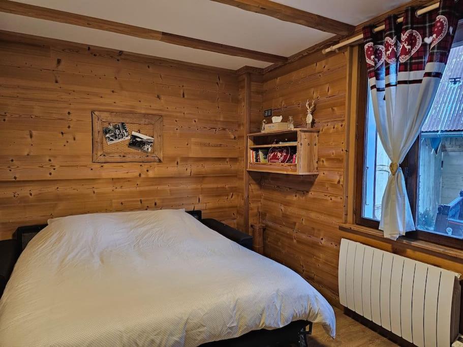 a bedroom with wooden walls and a bed with a window at Le Banc Des Seilles in Bonvillard