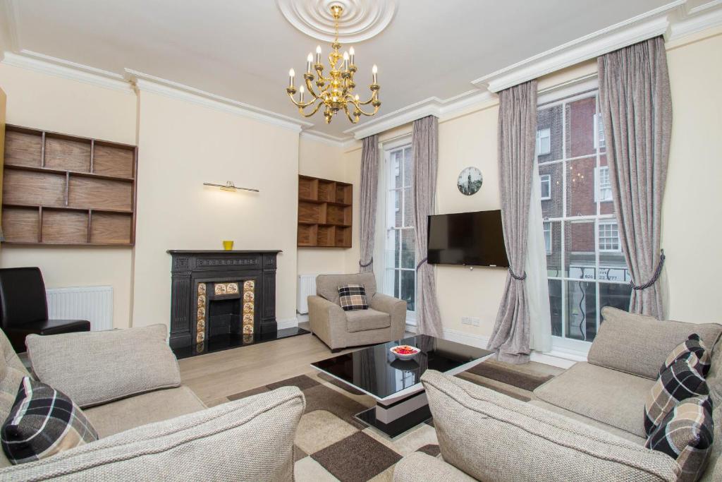 a living room with a fireplace and a chandelier at Marylebone Village Apartments in London