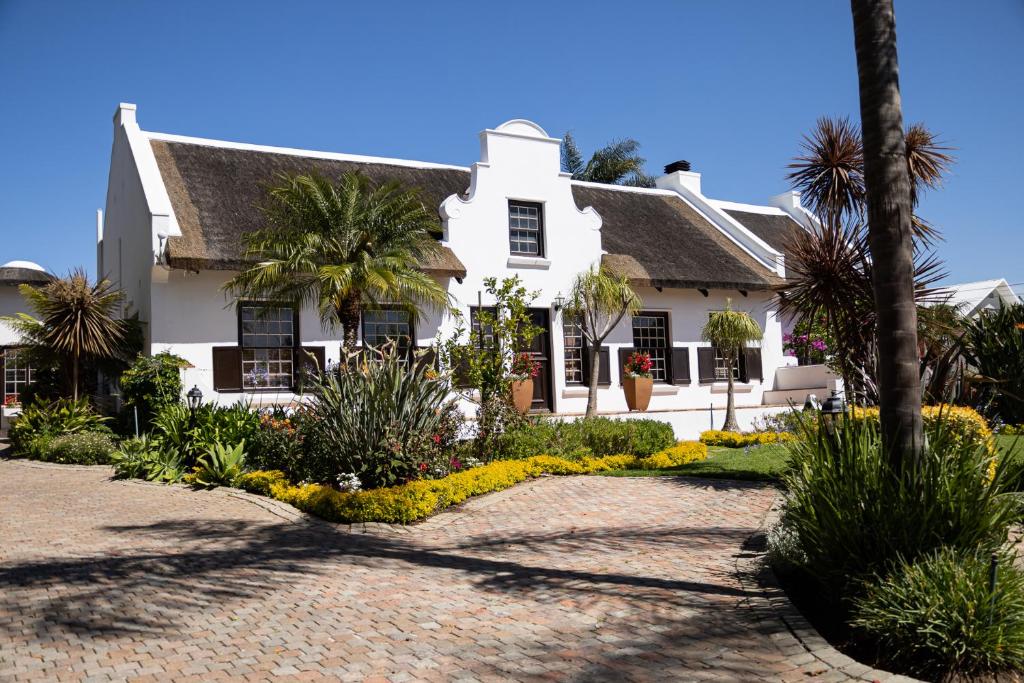 uma casa branca com palmeiras e plantas em Cape Village Lodge em Durbanville