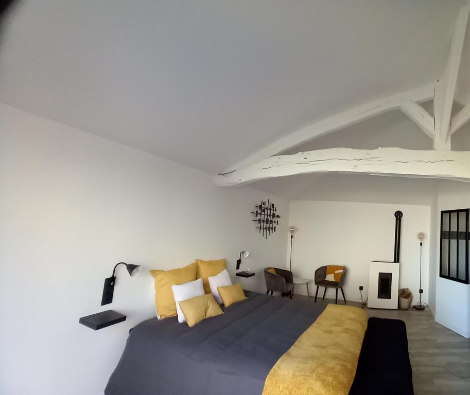 L'atelier d'André في Monbahus: غرفة نوم بسرير كبير مع مخدات صفراء