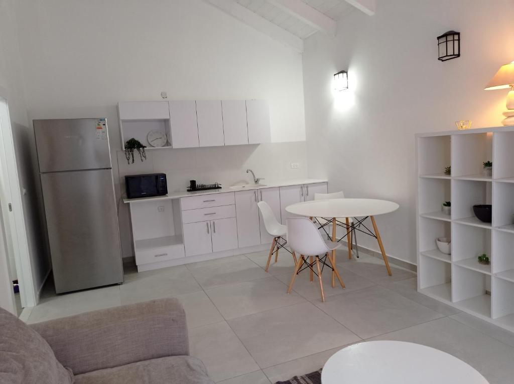 een witte keuken met een tafel en een koelkast bij צימר ברחובות- Tara ארוח Tzimmer יש ממד במתחם in Rechovot