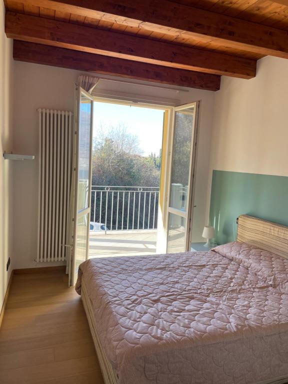 een slaapkamer met een groot bed en een balkon bij Sun Lake Iseo apartment in Sale Marasino