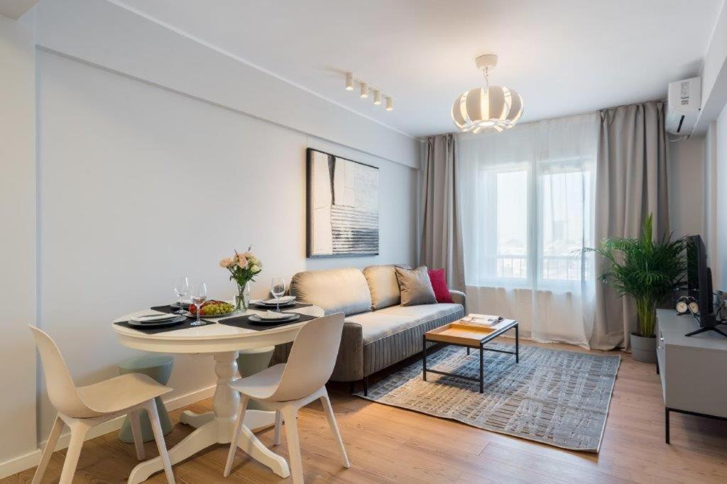 een woonkamer met een bank en een tafel bij Downtown Modern - 2BR Apartment in Boekarest